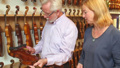 vendedor que aconseja al cliente que compra un violín