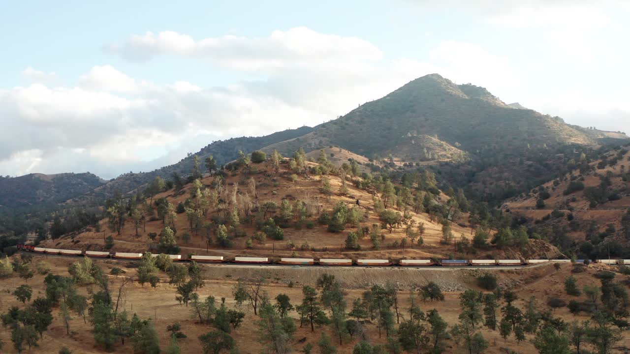 largo tren de carga pasando por montañas en tehachapi, california, aéreo