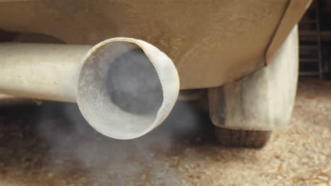 tracking probe lens shot of old car exhaust pipe from which smoke and fumes are pouring