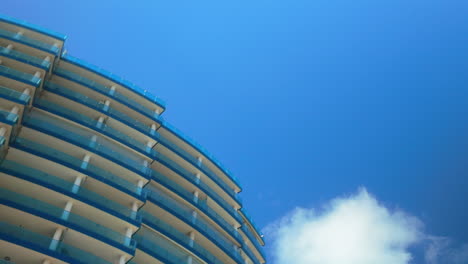 low-angle view of a modern high-rise building in gibraltar against a bright blue sky, showcasing its curved architecture