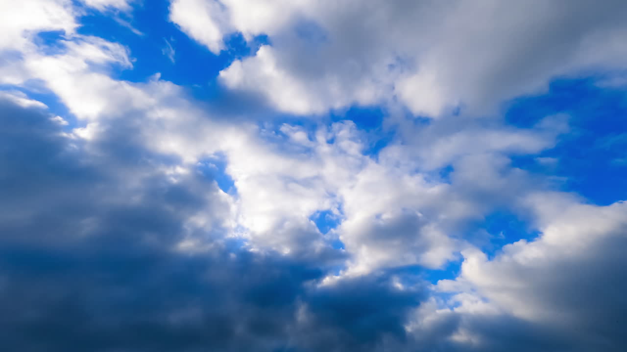 Beautiful azure sky is covered with thick heavy cloudscape. Low angle view on the grey clouds movement. Timelapse.