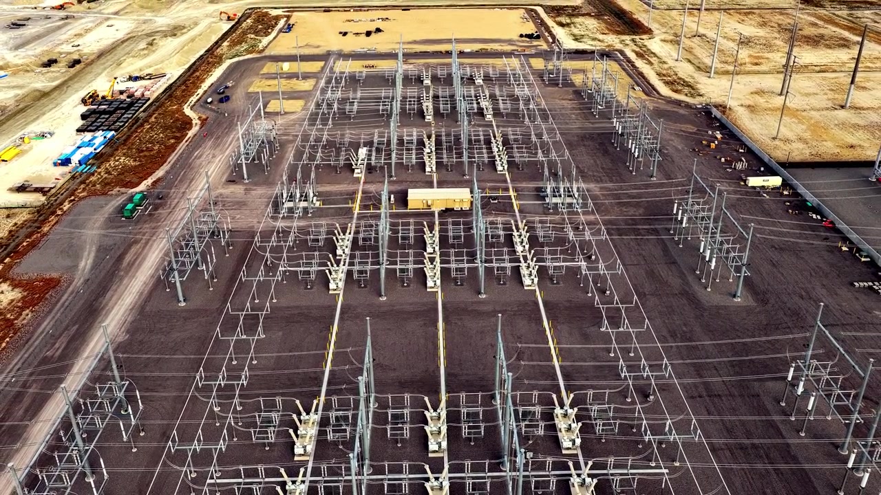 Aerial pullback and tilt reveal of a large electrical substation powering a hyperscale data center campus in Eagle Mountain, Utah.
