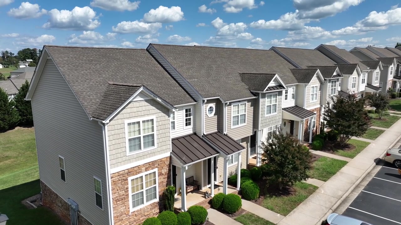Vista aérea de uma fileira moderna de casas com varanda em um bairro suburbano. Cidade americana durante um dia ensolarado com nuvens. Nova área residencial desenvolvida nos EUA. Close-up de drone.