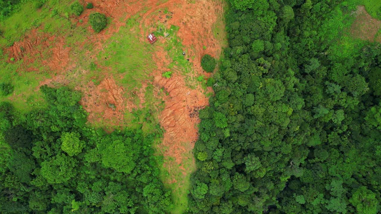 Rotating top‑view aerial of the Bataanes in Bagac, Bataan, highlighting the sharp contrast between reddish dirt clearings and dense green trees across the hilly terrain