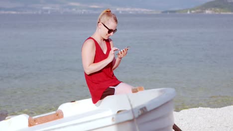 Young-Lady-Sitting-On-Beach-While-Using-Her-Mobile-Device-2