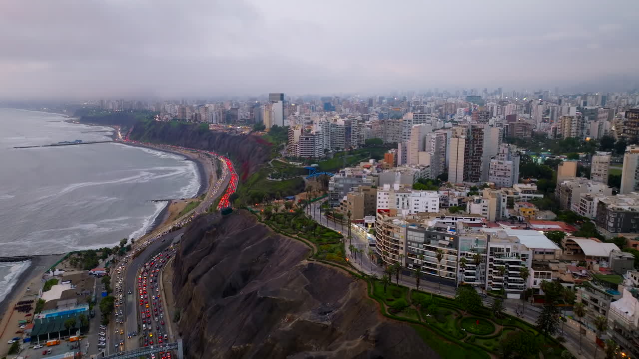 Pemandangan udara dari drone kota Lima saat senja, distrik Miraflores, tebing Costa Verde, dan lalu lintas padat di jalan raya pesisir, Peru