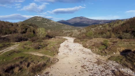 Aerial-over-dry-river-with-empty-river-bed-surrounded-by-vegetation