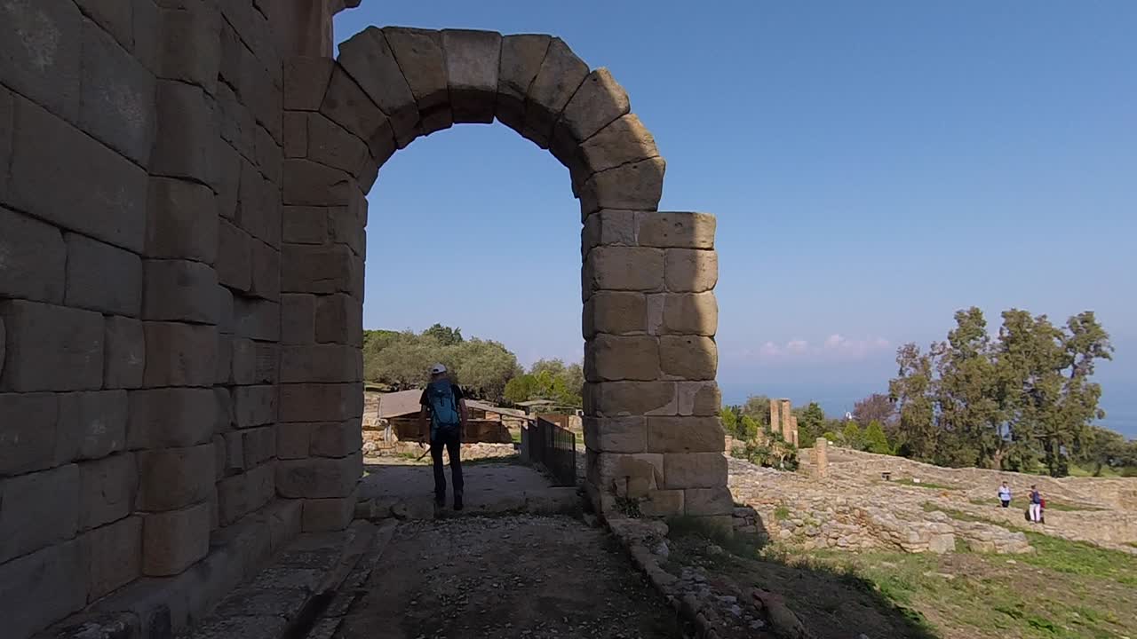 turista caminando bajo el arco en tinrdai, sicilia, italia