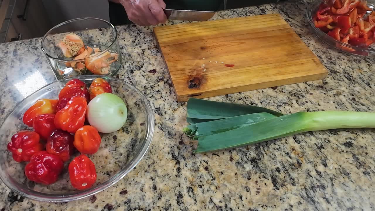 Chopping fresh green vegetables on wooden board senior hands close up