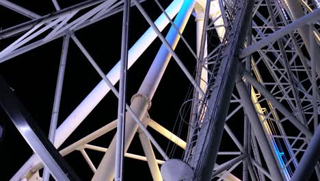 closeup on slowly rotating mechanism of colorful flickering iridescent ferris wheel in amusement park at nighttime