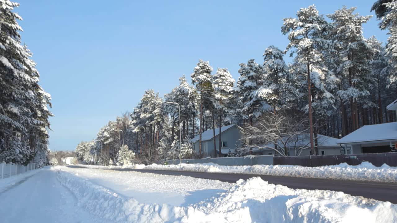Gorgeous urban street for cars and pedestrians in a neighborhood in Laagri that is covered in thick white fluffy snow during winter sunny day with large trees with snow civering them on the sides.
