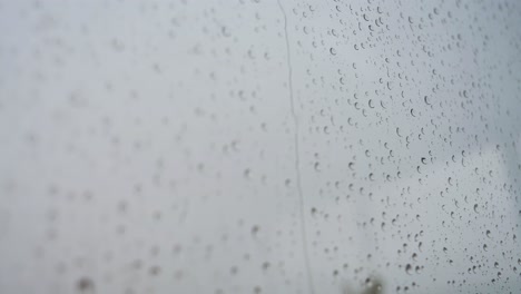 slow-motion footage of raindrops landing on a window glass during a heavy rain weather