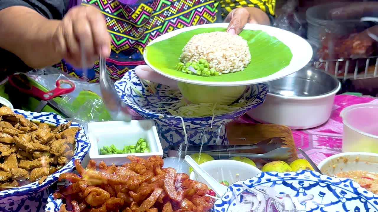 Close-up of a vendor preparing a colorful rice dish with various toppings at a market stall.