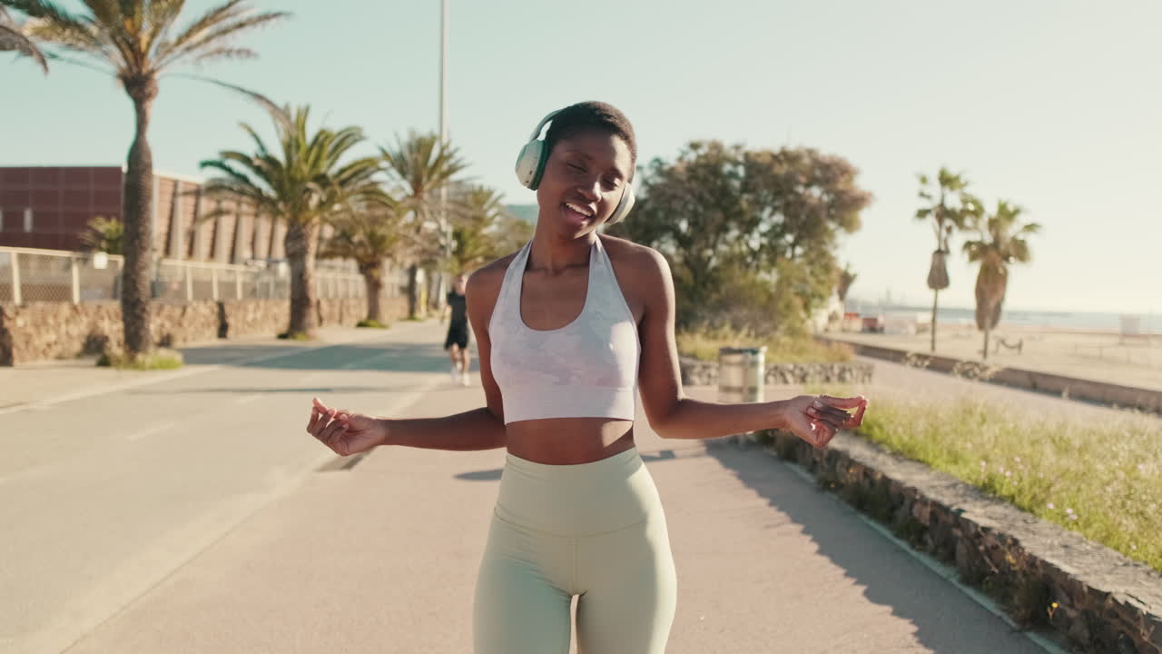 Happy African American Woman Dancing to Music with Headphones Outdoors