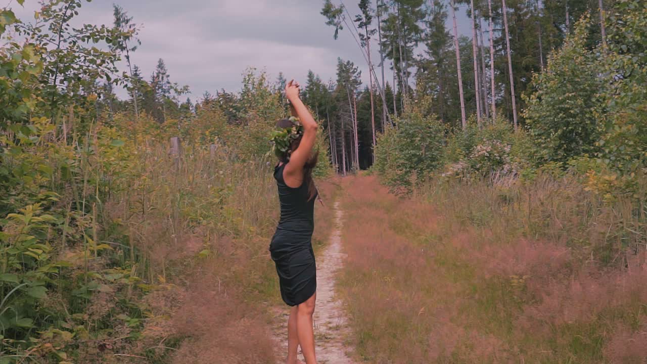 Free spirited woman wearing flower headdress walking joyful through forest, slow