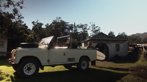 Surfer-Lädt-Surfbrett-Und-Neoprenanzug-In-Land-Rover