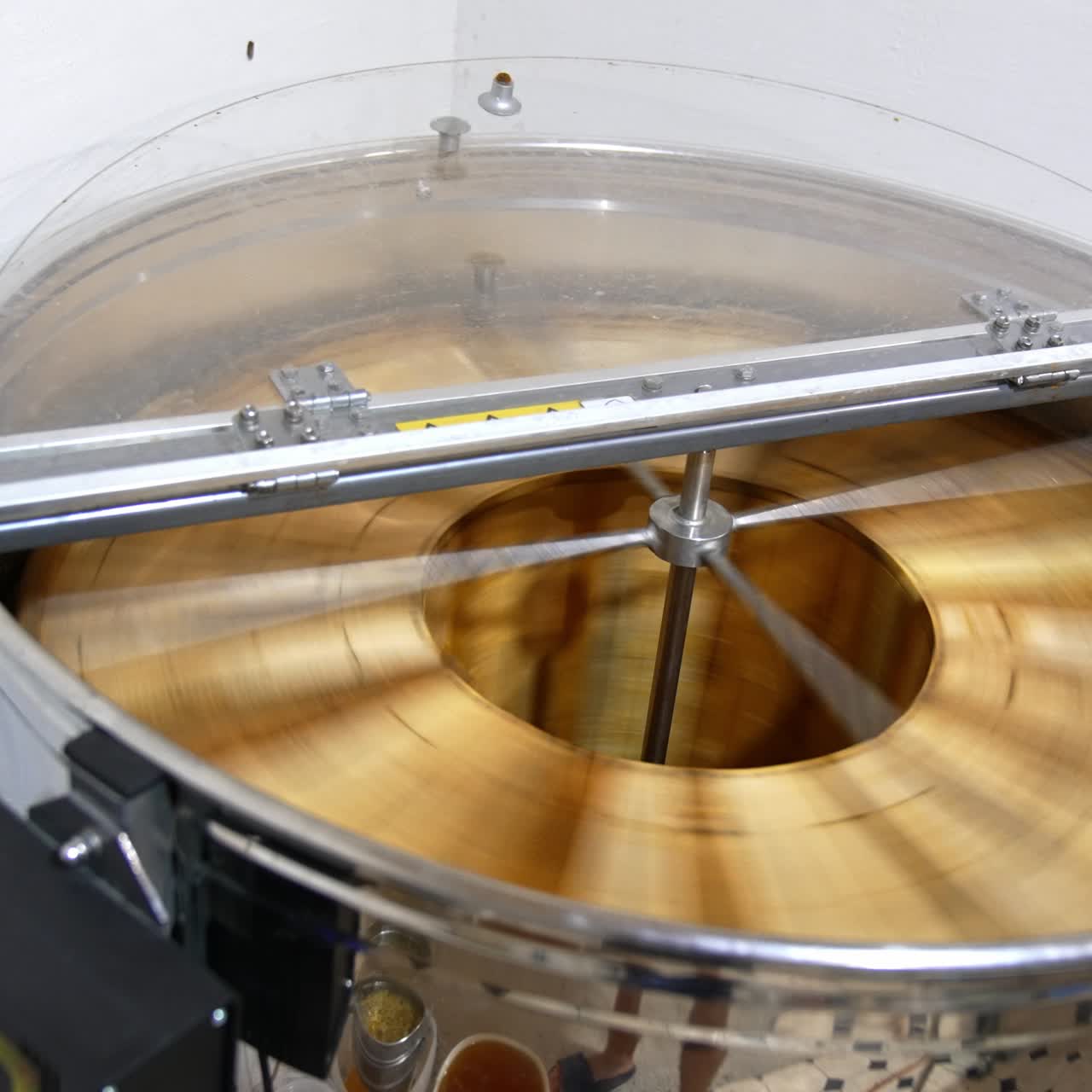 Metal barrel machine for honey extraction. Electric centrifuge spinning and rotating frames inside. View from top