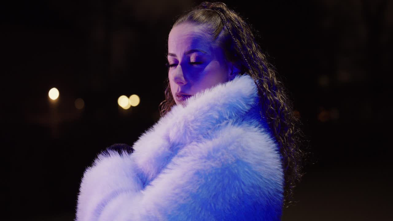Primo piano cinematografico di una donna in una strada notturna che indossa un cappotto di pelliccia bianco, mentre si volta a guardare indietro con una luce blu sul viso. Concept per solitudine urbana, atmosfera invernale e misteriosa vita notturna