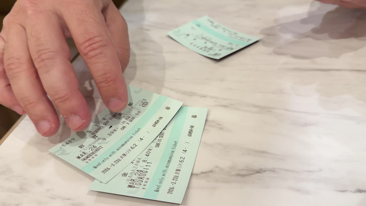 A traveler organizes green reserved seat tickets for a Japanese bullet train on a table