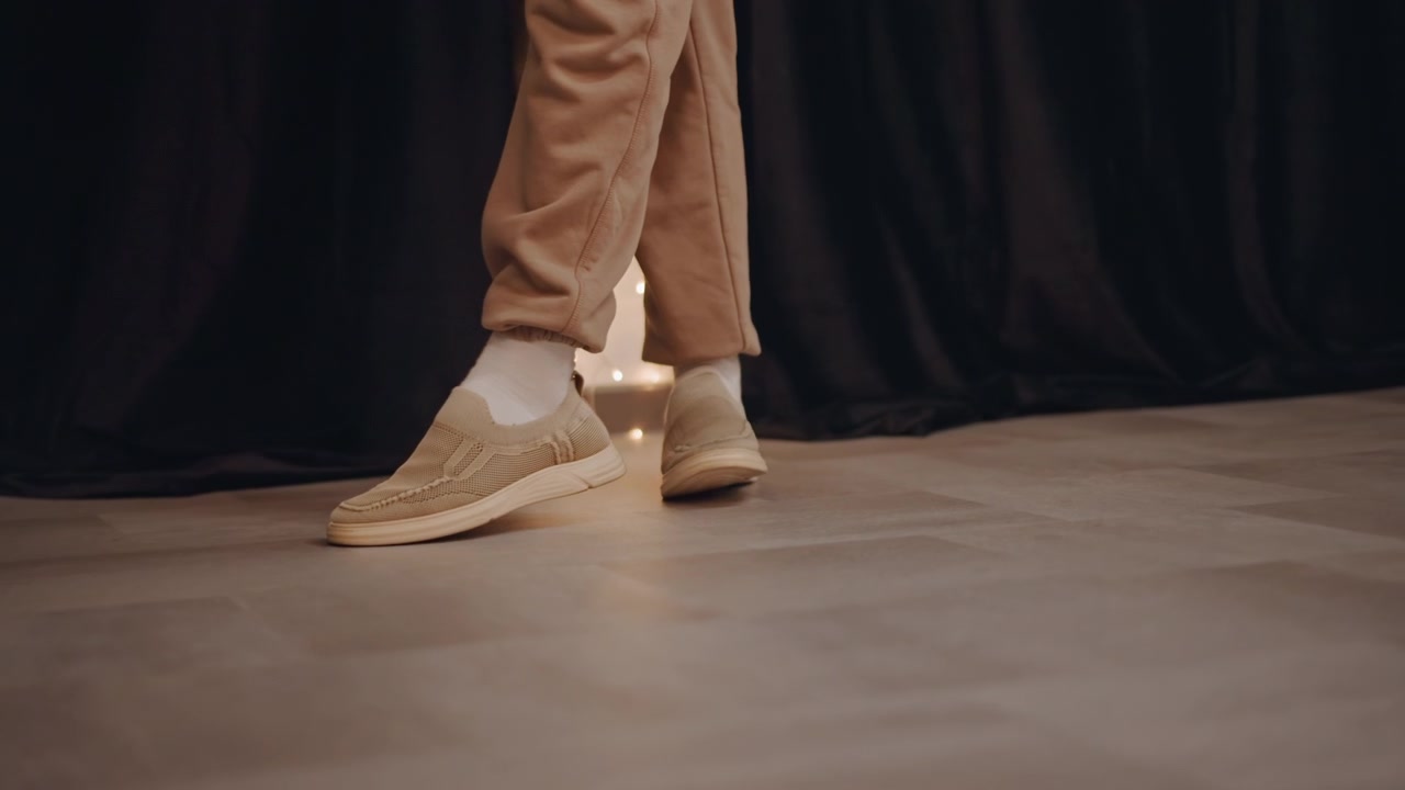 Sessione di allenamento a terra per sneaker, con esercizi di pivot e scivolamento, dove un coreografo dimostra tempismo, equilibrio e cadenza sul pavimento dello studio, in un'atmosfera didattica e a ritmo costante