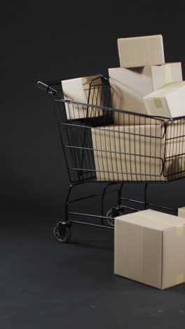 vertical video of shopping trolley with boxes and copy space over grey background