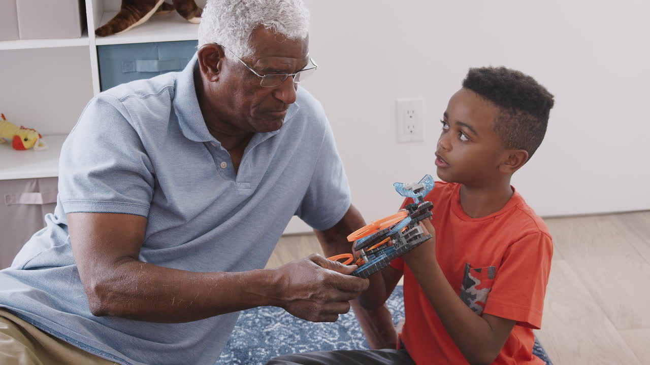 Nonno con il nipote seduti sul tappeto a casa che costruiscono insieme un modellino di elicottero