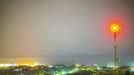 Telecommunications-tower-glows-red-at-night-as-cars-drive-under-night-sky-in-Malaga-Spain