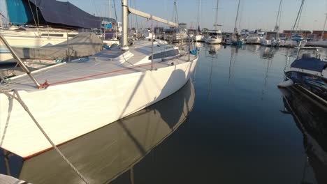 footage of a white sailing yachts moored on a walk on mooring with a blue sail sack and white mast next to other sea going vessels in a marina in durban