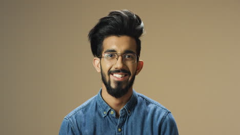 Young-handsome-indian-man-with-beard-and-glasses-looking-cheerfully-at-camera
