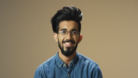 young handsome indian man with beard and glasses looking cheerfully at camera