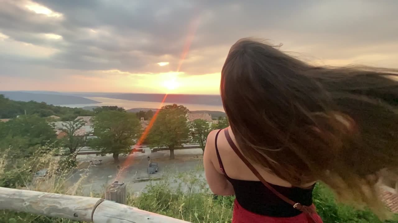 Gorgeous slow motion shot of a young Caucasian woman on a hill at sunset