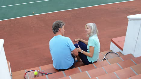 senior couple sitting on tennis court stairs 4k