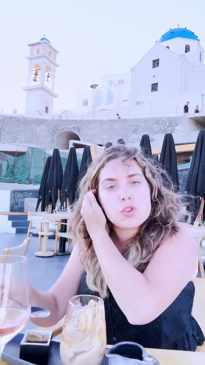 Influencer enjoying dessert and wine in santorini, greece