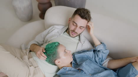 top view of young couple sitting on sofa, talking and caressing each other 1