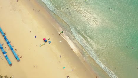 Flying-along-Karon-Beach-and-the-tourist-area-on-the-island-of-Phuket-in-Thailand,-the-Indian-Ocean-and-the-tourist-area-in-the-frame