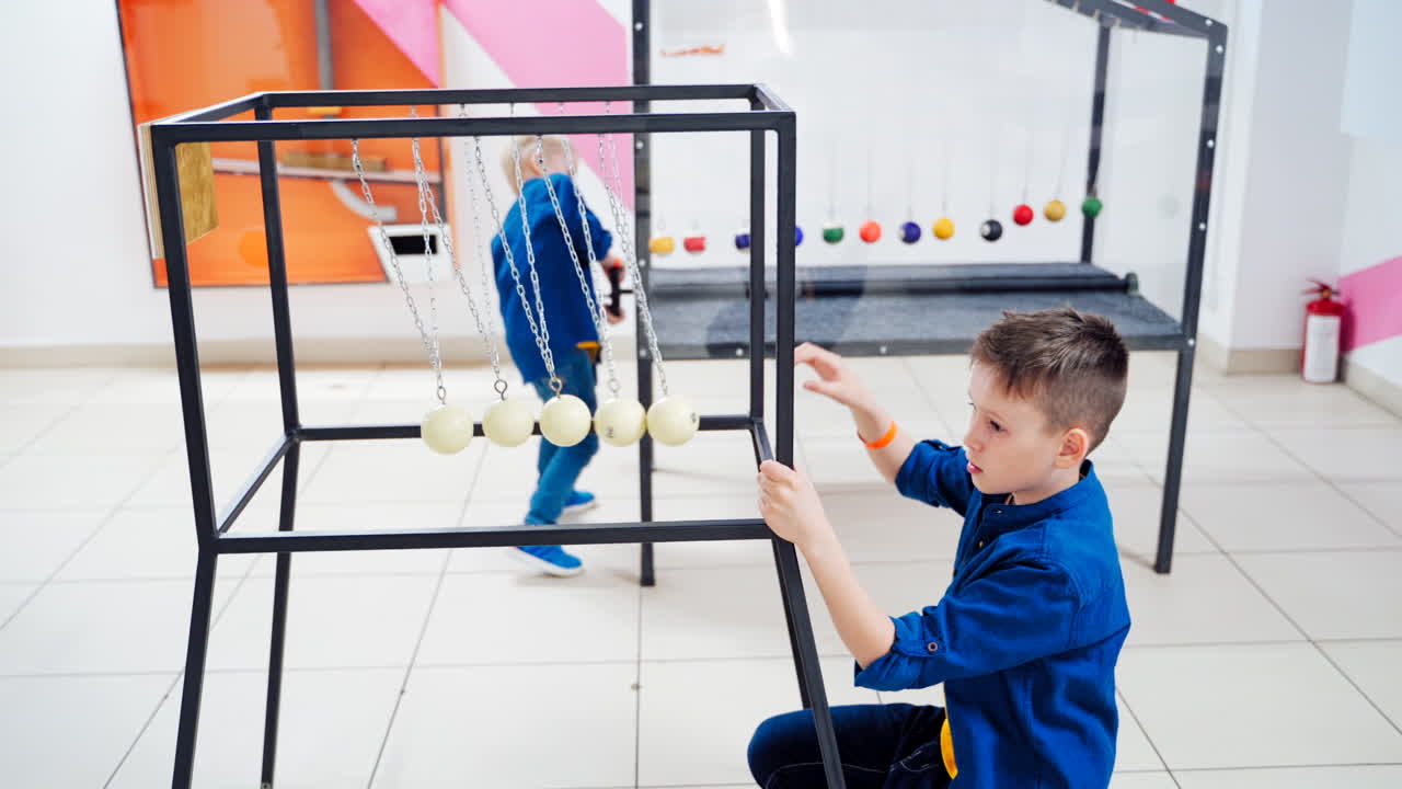 Children at the science center experimenting with Newton's cradle. The concept of physics. Museum of Science
