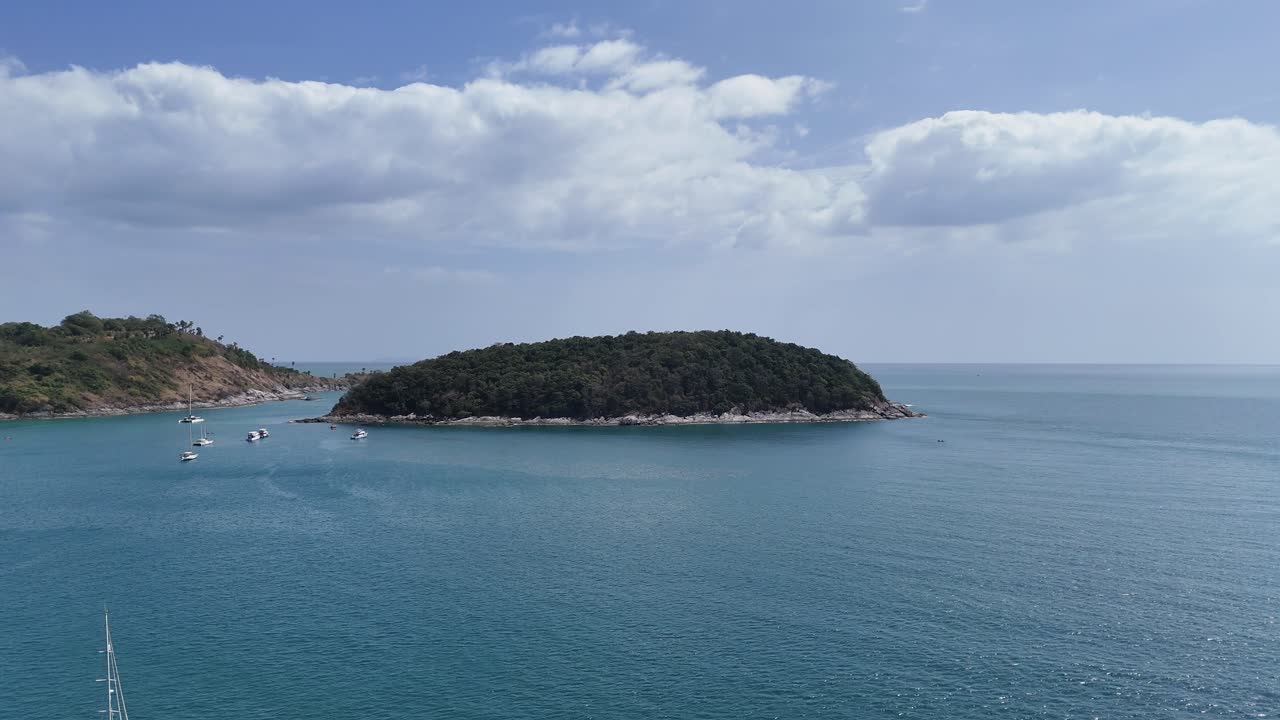 드론 영상은 태국 푸켓 근처의 평온한 바다 풍경과 보트를 은 하늘 아래 부드러운 카메라 움직임으로 포착합니다.