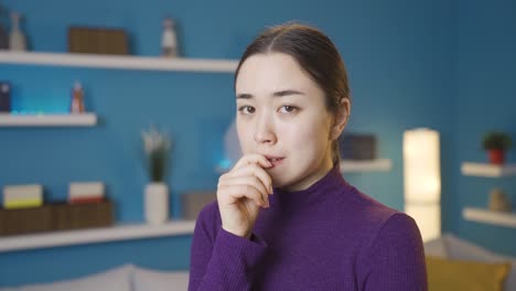 아시아 여성이 긴장해서 카메라를 쳐다보고 있습니다.