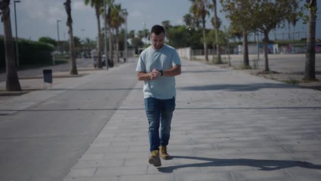 man checking watch on sidewalk
