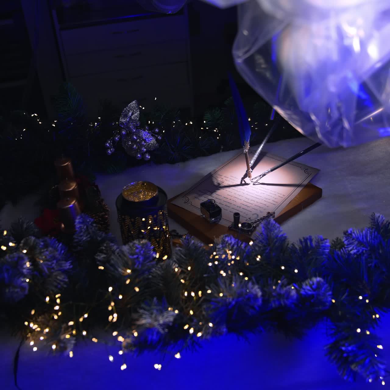 Surgical robotic arms coated with plastic perform writing on paper. Christmas decorations and garlands on surgical table. Dark surgical room backdrop