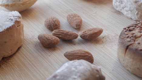 primer plano de almendras en una superficie de madera rodeada de dulces y pasteles navideños españoles