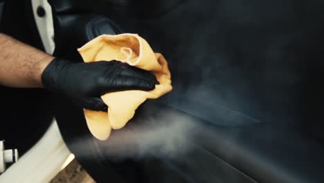 Male-wearing-black-gloves-cleaning-a-car-door-interior-with-steam