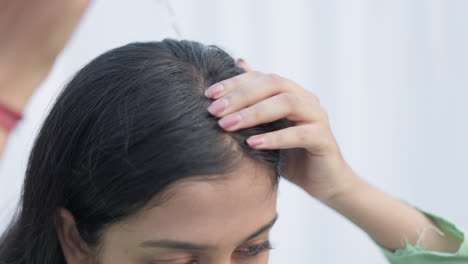 close up shot of a woman applying minoxidil with a dropper on alopecia head for hairloss treatment.