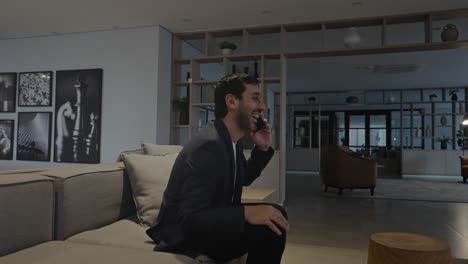 happy executive man sitting and enjoying a cheerful phone conversation in a modern and elegant living room.