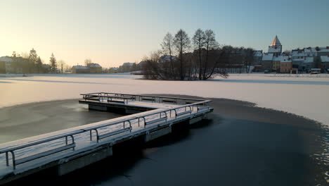 Schneebedeckte-Brücke-Am-Gefrorenen-Keramikteich-Bei-Sonnenaufgang-In-Der-Gemeinde-Gorowo-Ilaweckie,-Polen