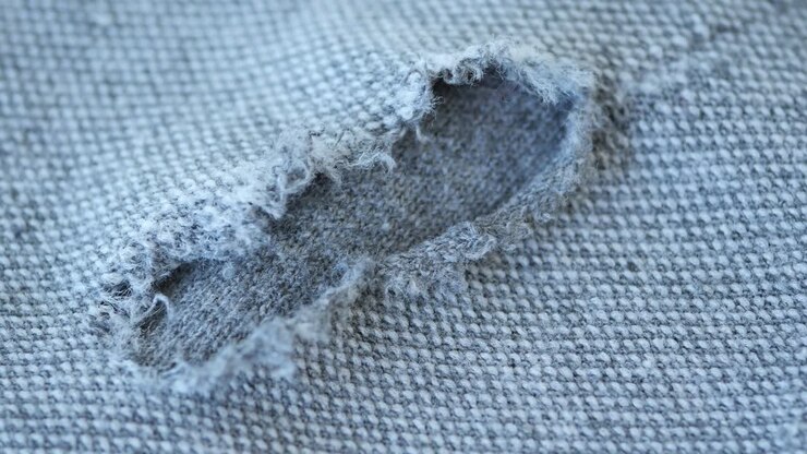 nahaufnahme eines zerrissenen grauen pullovers