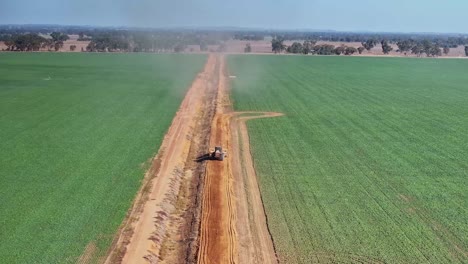 aerial of a tractor pulling a small road grader along a dirt farm road