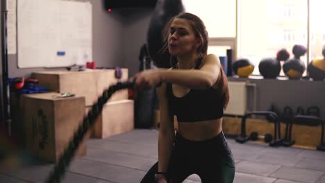 Starkes,-Sportliches-Brünettes-Mädchen-In-Den-Zwanzigern,-Das-Im-Fitnessstudio-Battle-Ropes-Training-Durchführt.