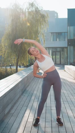 joven corredora en forma estirando el cuerpo calentándose antes del entrenamiento preparándose para correr al aire libre en el parque de la ciudad