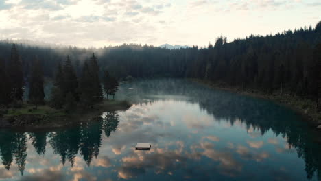 beautiful reflection of a lush forest surrounding lake - aerial shot